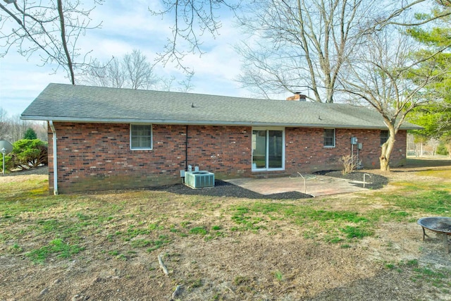 back of house featuring brick siding, central AC unit, a patio area, and a chimney