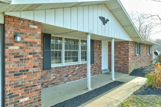 property entrance featuring board and batten siding, a porch, and brick siding