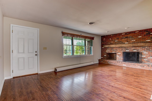 unfurnished living room featuring wood finished floors, baseboards, visible vents, a baseboard radiator, and a brick fireplace