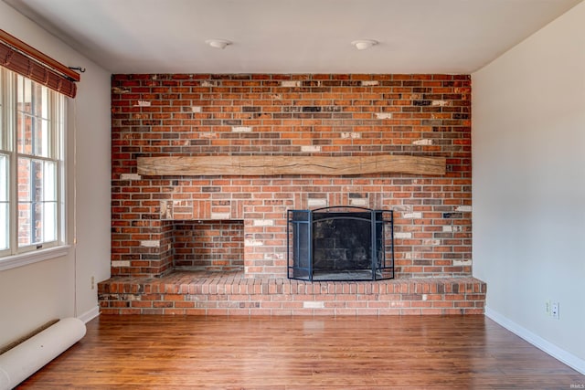 unfurnished living room with wood finished floors, a fireplace, and baseboards