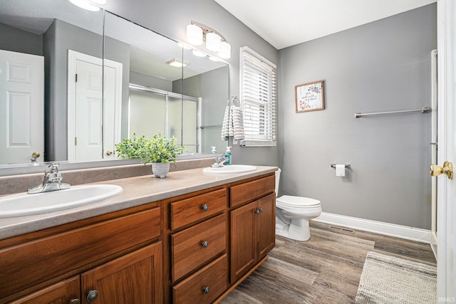 full bath featuring double vanity, wood finished floors, a stall shower, and a sink