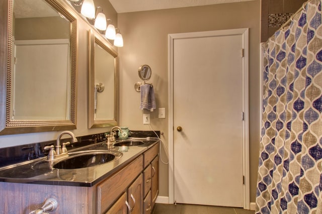 full bath featuring a sink, curtained shower, double vanity, and tile patterned flooring