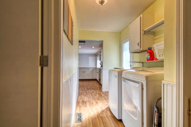 washroom featuring cabinet space, a wainscoted wall, independent washer and dryer, and light wood-style floors