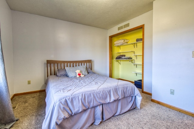 carpeted bedroom with baseboards, visible vents, and a textured ceiling