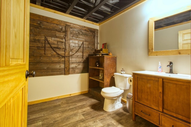 bathroom with vanity, toilet, wood finished floors, and baseboards