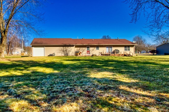 back of house with a deck, an attached garage, and a lawn