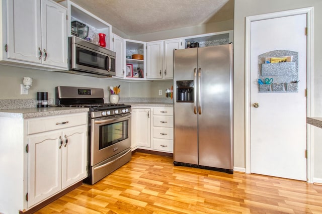 kitchen featuring open shelves, light wood-style floors, appliances with stainless steel finishes, and a textured ceiling