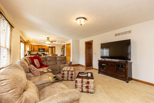 living room with light colored carpet, baseboards, visible vents, and a ceiling fan