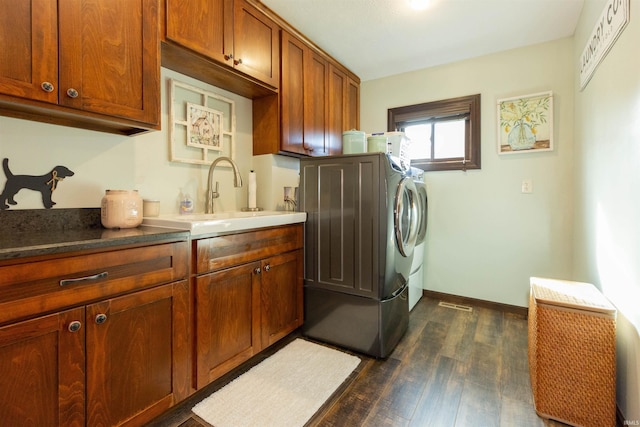 washroom featuring baseboards, dark wood finished floors, washing machine and dryer, cabinet space, and a sink