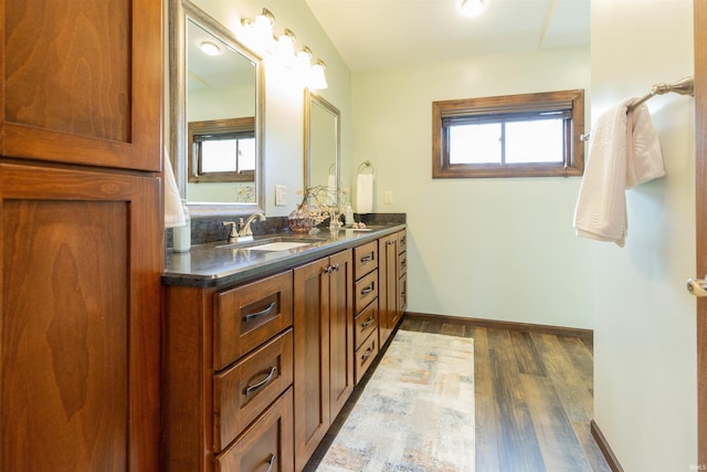 full bathroom featuring double vanity, wood finished floors, baseboards, and a sink