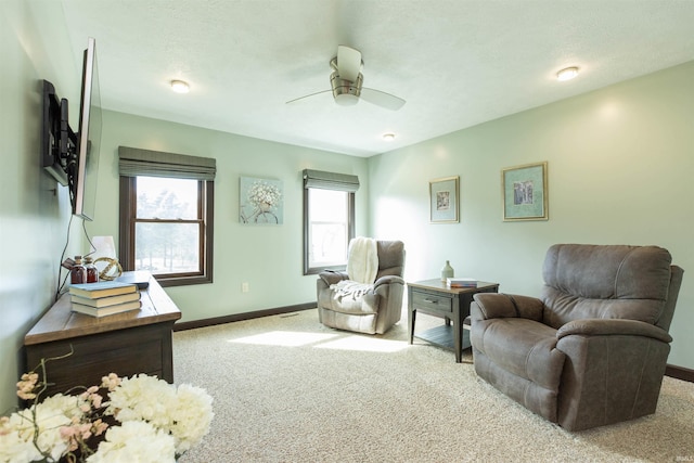 living area with baseboards, ceiling fan, and carpet flooring