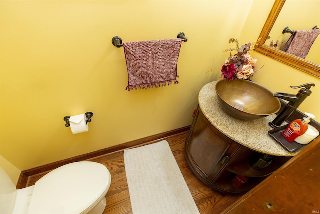 half bathroom with toilet, vanity, and baseboards