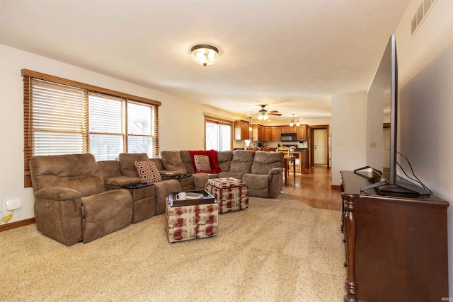 living area featuring visible vents, baseboards, and ceiling fan