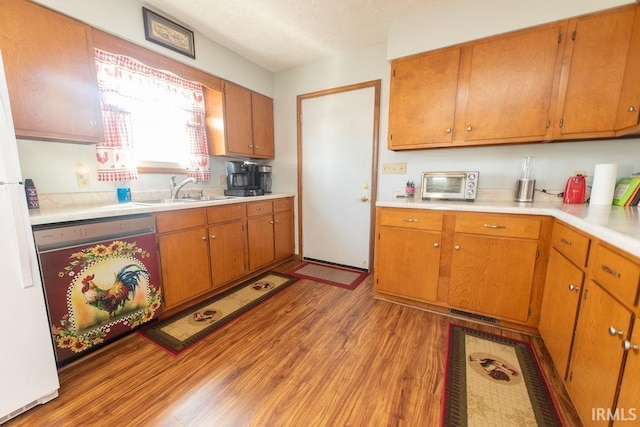 kitchen featuring light wood-style flooring, a sink, a toaster, dishwasher, and light countertops