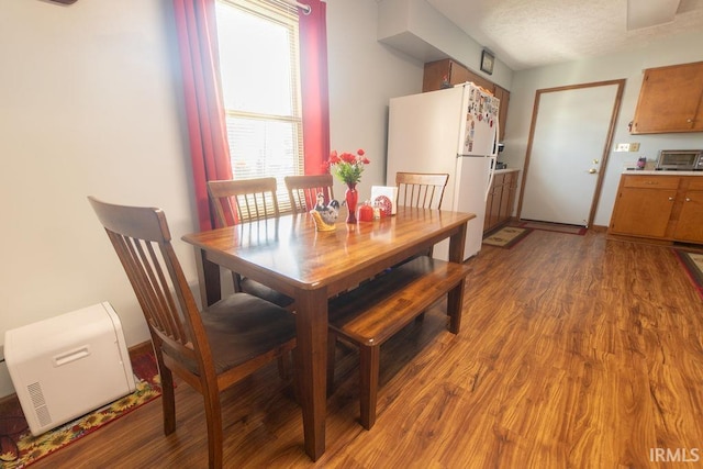 dining space with a toaster, light wood-type flooring, and a textured ceiling