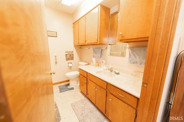 bathroom with baseboards, toilet, vanity, and a textured ceiling