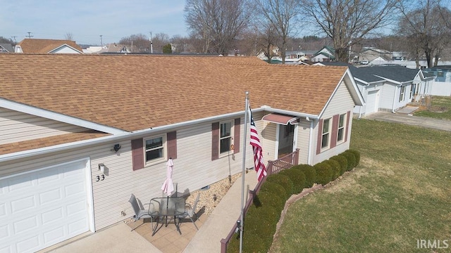 view of home's exterior featuring a lawn, a shingled roof, and a garage