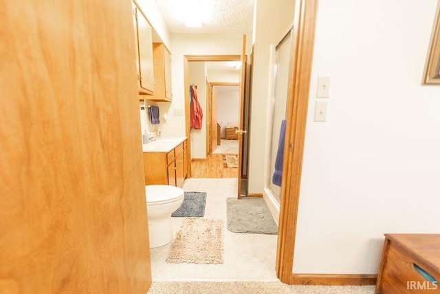 bathroom with vanity, a textured ceiling, a shower stall, and toilet