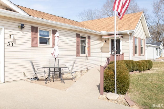 exterior space with a yard, a patio, and roof with shingles