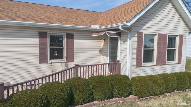 view of exterior entry with roof with shingles