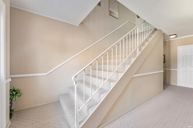 staircase with crown molding and carpet floors