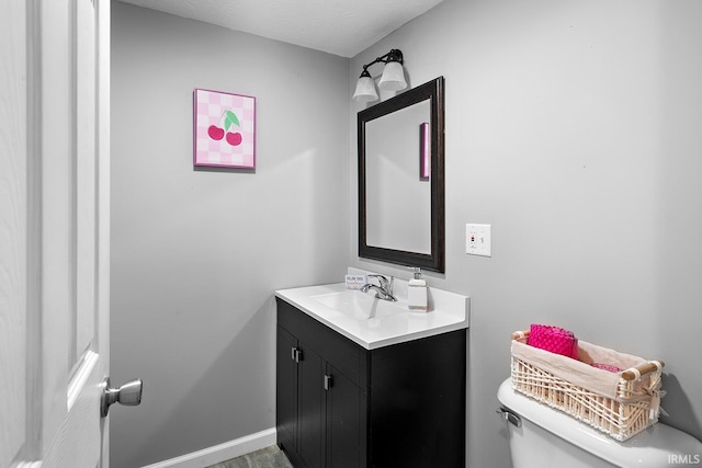 bathroom with baseboards, toilet, and vanity