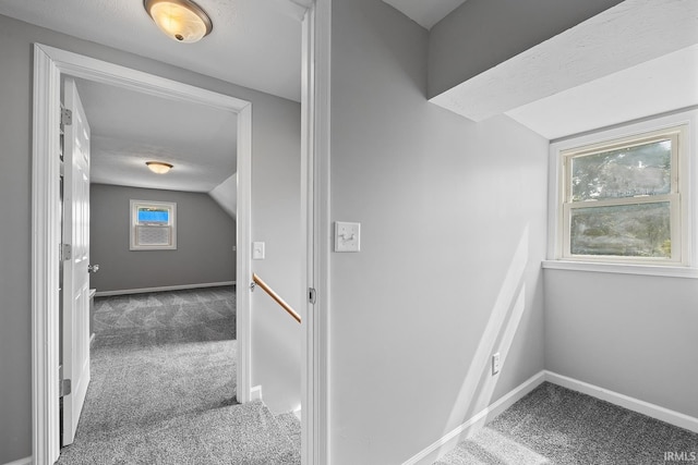 hallway featuring baseboards, carpet, and vaulted ceiling