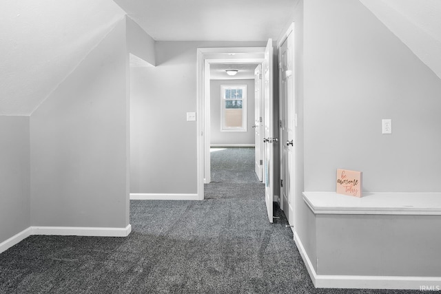 corridor with baseboards, carpet floors, and vaulted ceiling