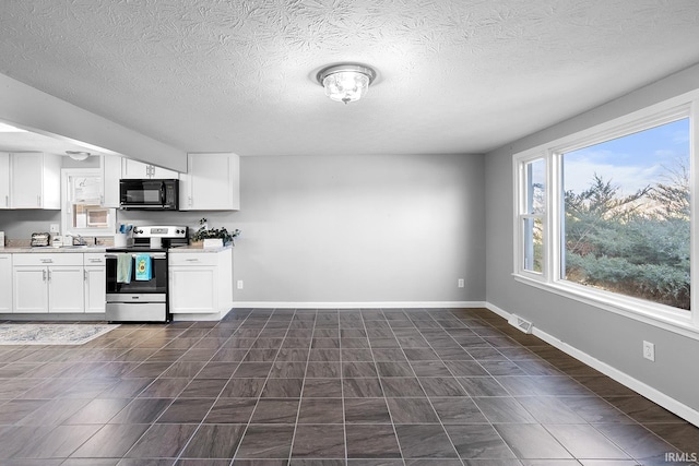 kitchen with baseboards, visible vents, stainless steel electric stove, light countertops, and black microwave