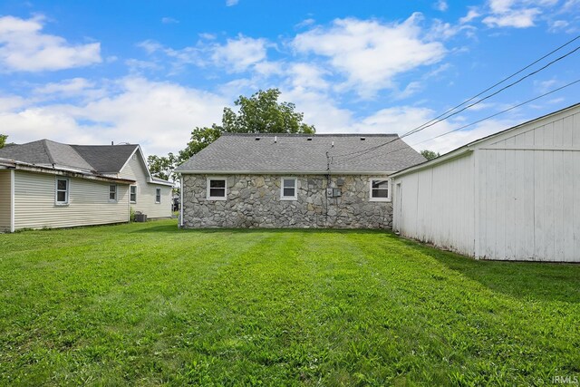 back of property with a lawn and stone siding