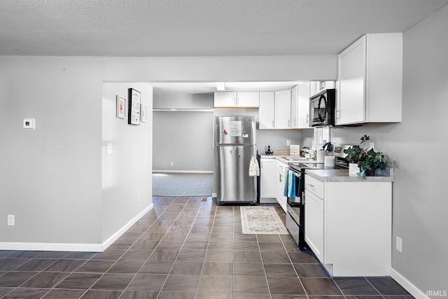 kitchen featuring white cabinetry, stainless steel appliances, light countertops, and baseboards