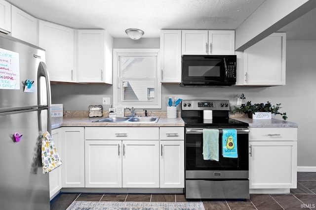 kitchen with white cabinets, stainless steel appliances, light countertops, and a sink