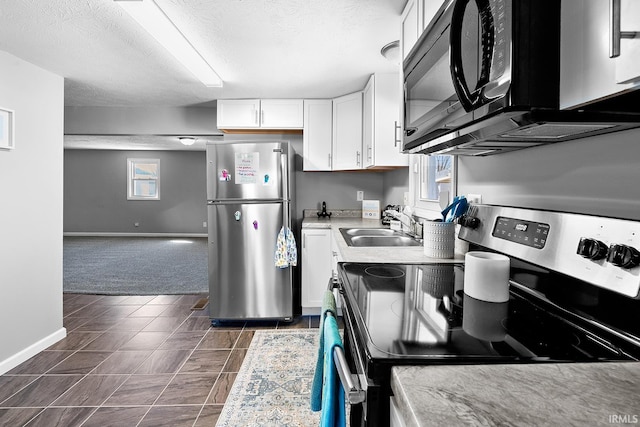 kitchen featuring baseboards, stainless steel appliances, white cabinets, a textured ceiling, and a sink