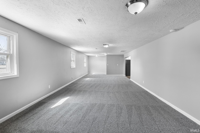 carpeted spare room with baseboards and a textured ceiling