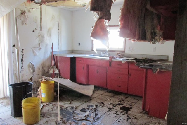 kitchen featuring a sink, light floors, and red cabinets