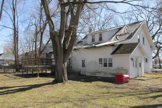 rear view of house featuring a wooden deck, a lawn, and a chimney