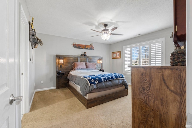 bedroom with visible vents, a ceiling fan, a textured ceiling, baseboards, and light colored carpet