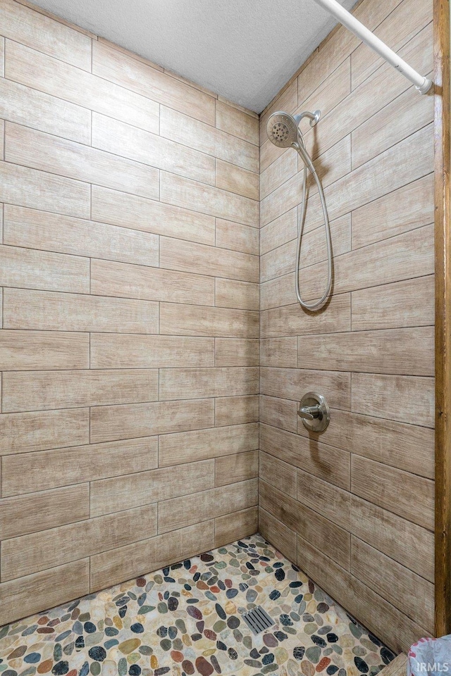 bathroom featuring tiled shower and a textured ceiling