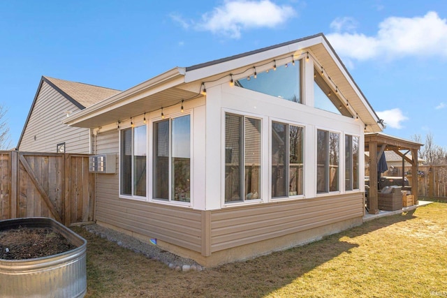 view of side of home featuring a lawn, a sunroom, and fence