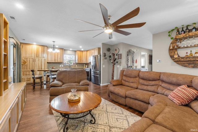 living area featuring visible vents, dark wood-style floors, and ceiling fan with notable chandelier