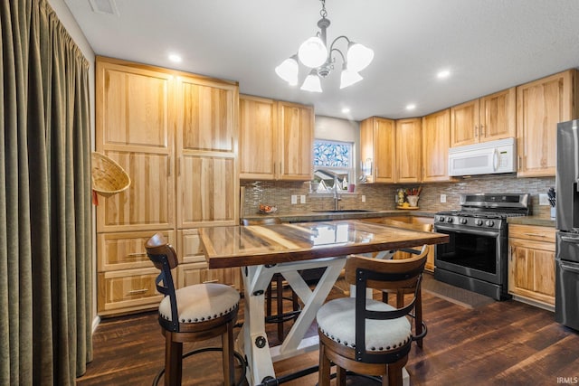 kitchen featuring light brown cabinetry, dark wood-style flooring, appliances with stainless steel finishes, and a sink