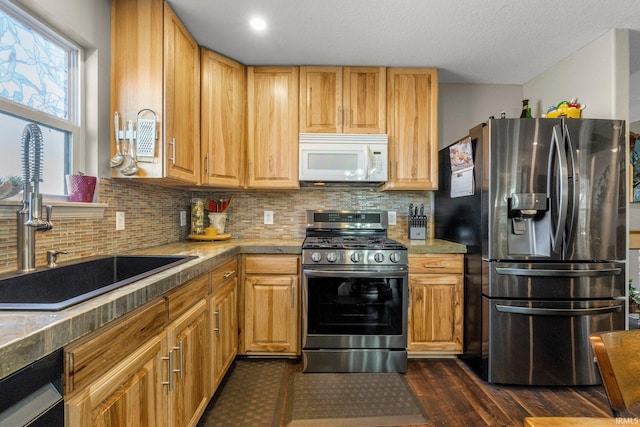 kitchen featuring dark wood-style flooring, backsplash, stainless steel appliances, and a sink