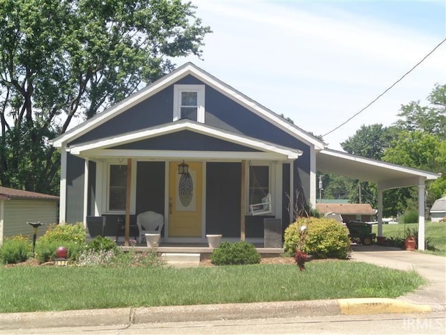 bungalow-style house with a carport, covered porch, driveway, and a front lawn