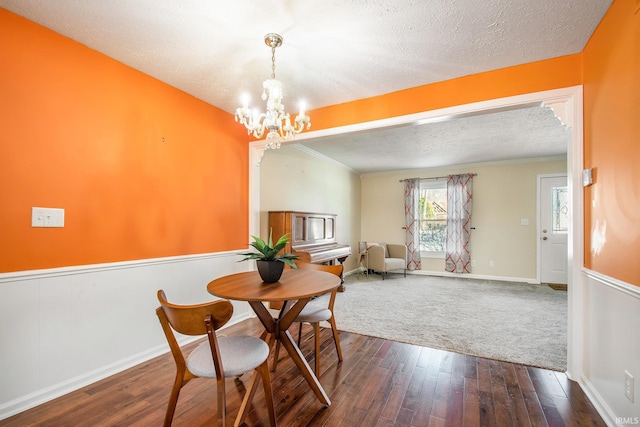 dining area with a chandelier, a textured ceiling, dark wood finished floors, and ornamental molding