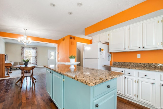 kitchen featuring blue cabinets, white cabinets, a center island, and freestanding refrigerator