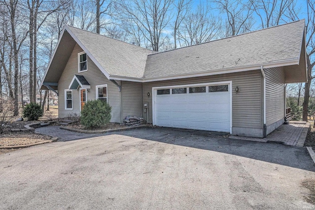 view of front of property featuring an attached garage, driveway, and a shingled roof