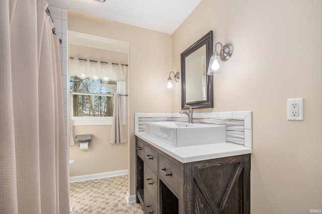 bathroom featuring toilet, vanity, and baseboards