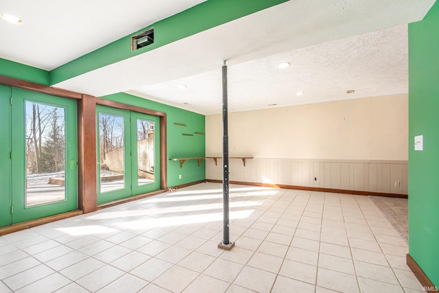 unfurnished room featuring a textured ceiling, tile patterned floors, recessed lighting, and wainscoting