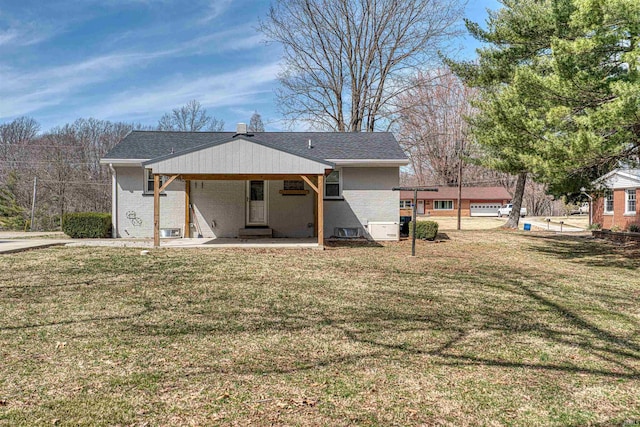 rear view of house featuring a patio, a lawn, brick siding, and a shingled roof