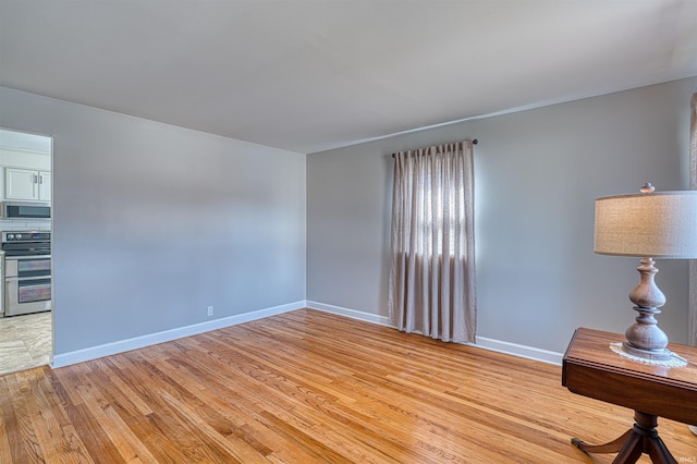 unfurnished room with light wood finished floors and baseboards